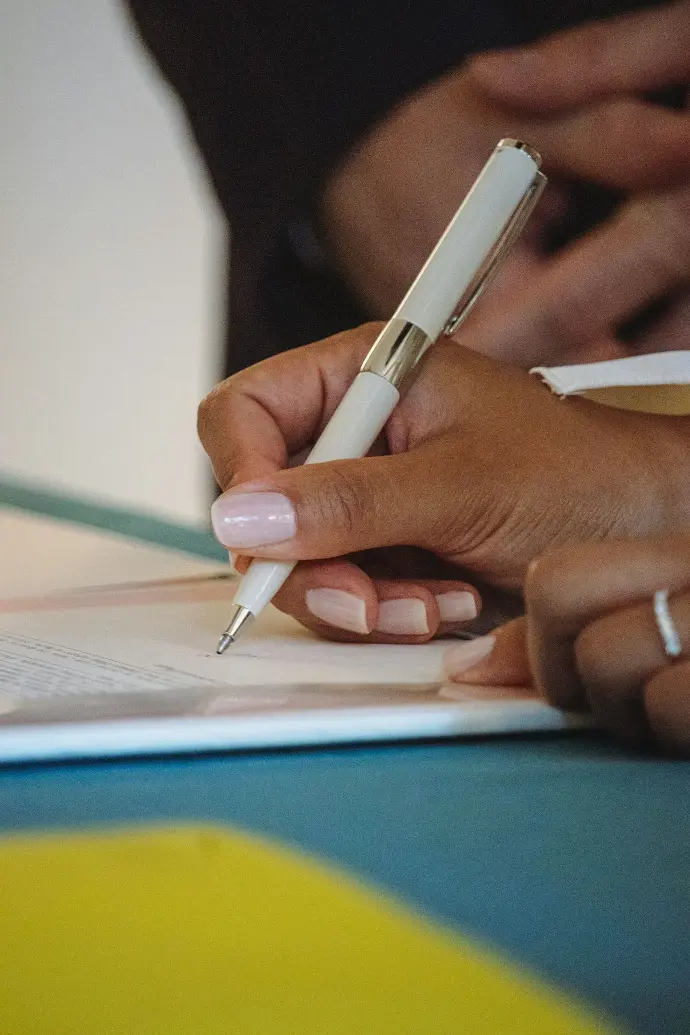 A person writing on a piece of paper with a pen